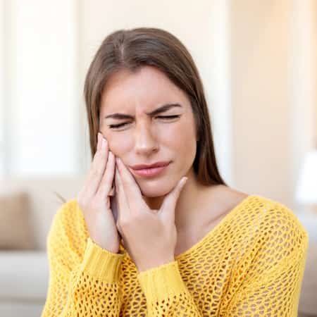 woman holding jaw from tmj pain